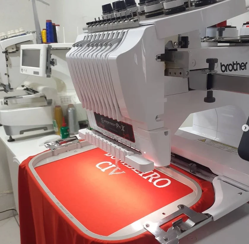 Máquina de bordado computadorizada personalizando um tecido vermelho